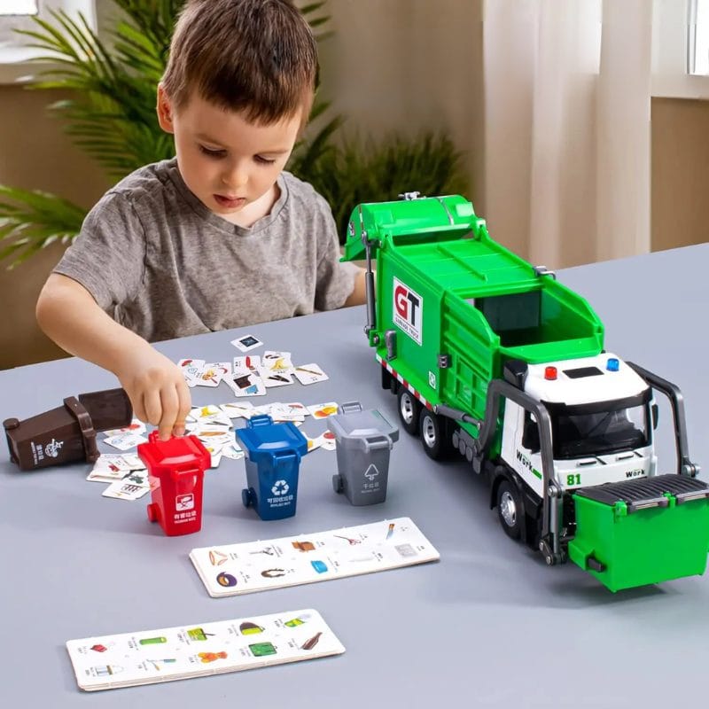 Copil jucându-se cu camionul de reciclare verde, pubelele și cartonașele de sortare