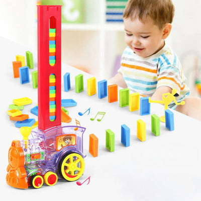 Copil lângă trenulețul electric și un traseu de piese domino multicolore.